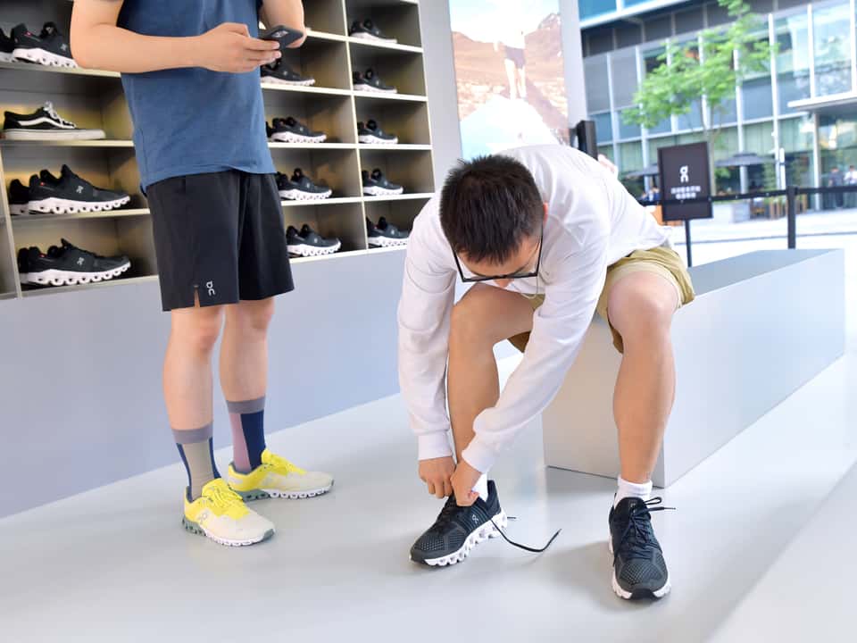 A customer trying on On Running shoes in an On Running store.